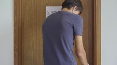 Gönüllü bir adam, kendini karantinaya almış biri için yemek dağıtıyor. Kapıda karantina işareti var. Ev kavramında karantina. Tecrit edilmiş insanlar için yemek teslimatı. COVID-19 kavramı