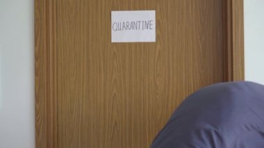 Gönüllü bir adam, kendini karantinaya almış biri için yemek dağıtıyor. Kapıda karantina işareti var. Ev kavramında karantina. Tecrit edilmiş insanlar için yemek teslimatı. COVID-19 kavramı