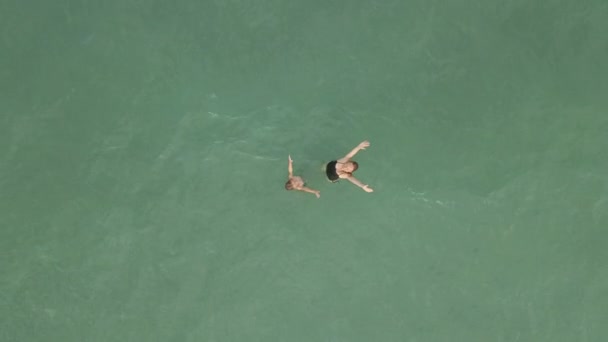 Lançamento em câmara lenta. Vista de cima para baixo em uma mãe e filho se divertindo em um mar azul — Vídeo de Stock