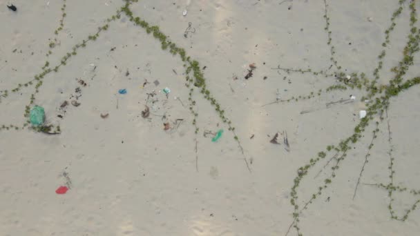 Vista aérea de arriba hacia abajo en una hermosa playa de arena cubierta de basura, en su mayoría de plástico. Debido a las restricciones COVID-19 los resorts están cerrados, por lo que nadie limpia playas en países tropicales — Vídeo de stock