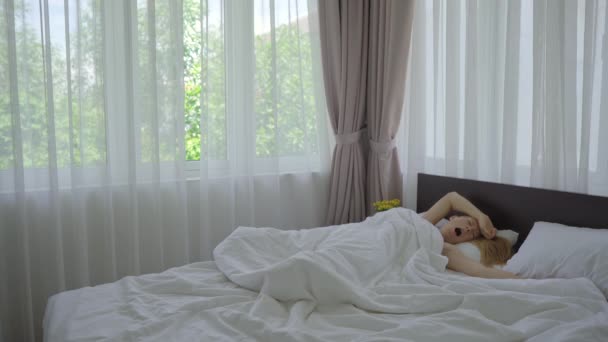 Egy fiatal nő felébred a hálószobájában. Boldog és kipihent. — Stock videók
