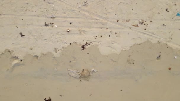 Αεροφωτογραφία από πάνω προς τα κάτω σε μια όμορφη αμμώδη παραλία καλυμμένη με σκουπίδια, κυρίως πλαστικά. Λόγω των περιορισμών COVID-19 θέρετρα είναι κλειστά, έτσι κανείς δεν καθαρίζει παραλίες σε τροπικές χώρες — Αρχείο Βίντεο