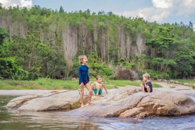 Güneşli bir yaz gününde, güzel bir nehirde oynayan genç sevimli çocuklar. Doğadaki çocukluk.