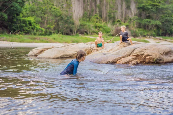Jóvenes chicos lindos jugando en el agua en un hermoso río en un día soleado de verano. La infancia en la naturaleza — Foto de Stock
