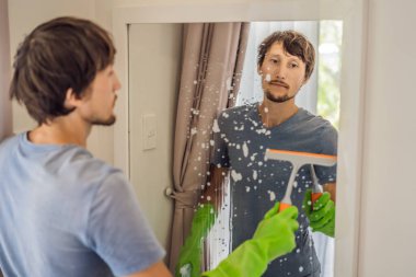 Otelde ayna temizleyen genç adam.