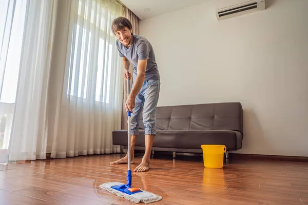 Joven con piso de limpieza de fregona en casa —  Fotos de Stock