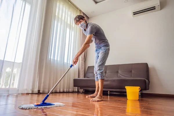 Joven con piso de limpieza de fregona en casa durante coronavirus COVID 19 — Foto de Stock