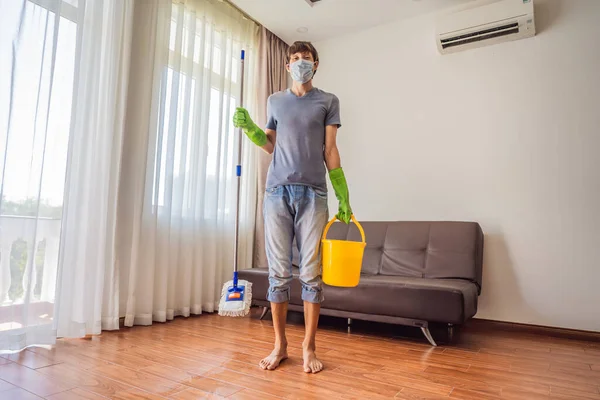 Joven con piso de limpieza de fregona en casa durante coronavirus COVID 19 — Foto de Stock