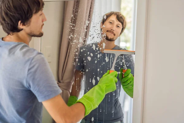 Young man cleaning mirror at home hotel — Stock Photo, Image