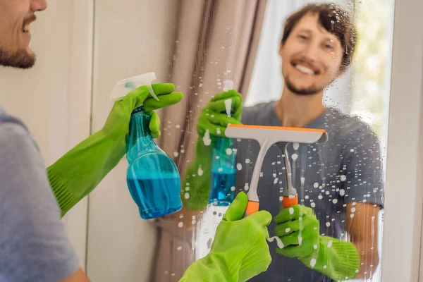 Joven hombre limpieza espejo en casa hotel — Foto de Stock