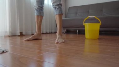 Genç bir adam bir dairede yerleri yıkıyor. Temizlik hizmeti konsepti. Cinsiyet eşitliği kavramı