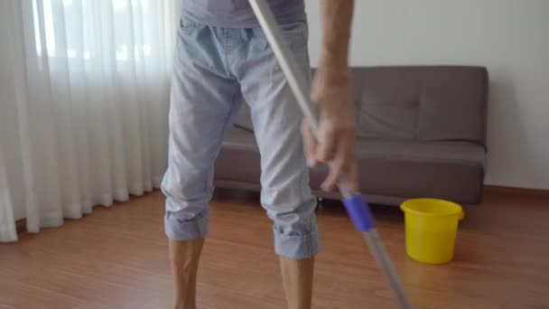 Un joven lava el suelo en un apartamento. Servicio de limpieza concepto. Concepto de igualdad de género — Vídeos de Stock
