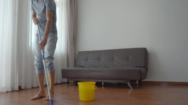 Genç bir adam bir dairede yerleri yıkıyor. Temizlik hizmeti konsepti. Cinsiyet eşitliği kavramı