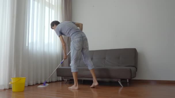 Un joven lava el suelo en un apartamento. Servicio de limpieza concepto. Concepto de igualdad de género — Vídeo de stock