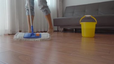 Genç bir adam bir dairede yerleri yıkıyor. Temizlik hizmeti konsepti. Cinsiyet eşitliği kavramı