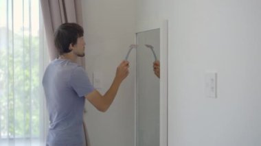 Genç bir adam cam temizleme sıvısı kullanarak aynayı yıkar. Temizlik hizmeti konsepti. Cinsiyet eşitliği kavramı