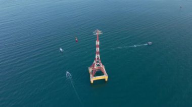 Bir teleferiğin deniz üzerindeki havadan yavaş çekimi, bazı tekneler yüzüyor.