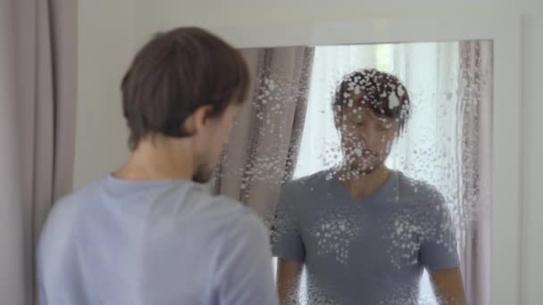 Un giovane lava uno specchio usando un liquido detergente per vetri. concetto di servizio di pulizia. Concetto di uguaglianza di genere — Video Stock