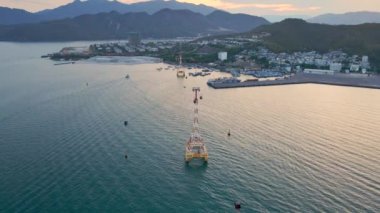 Denizin üzerinde bir teleferiğin yavaş çekim görüntüsü. Vietnam, Nha Trang şehrinin güzel gün batımı görüntüsü.