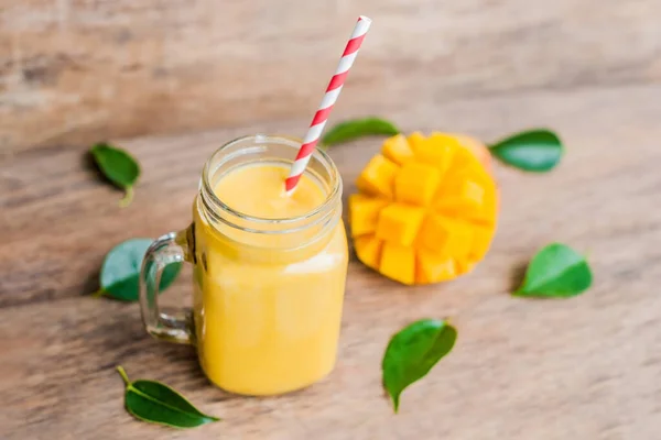 Juicy smoothie from mango in glass mason jar with striped red straw on old wooden background. Egészséges életkoncepció, másolás tér — Stock Fotó