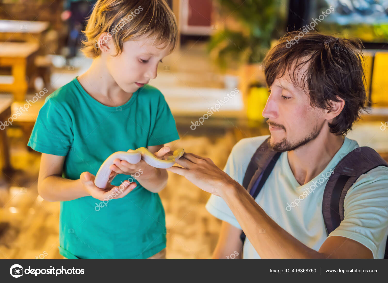 Smiling boy and his father holding python in hands Stock Photo by ...