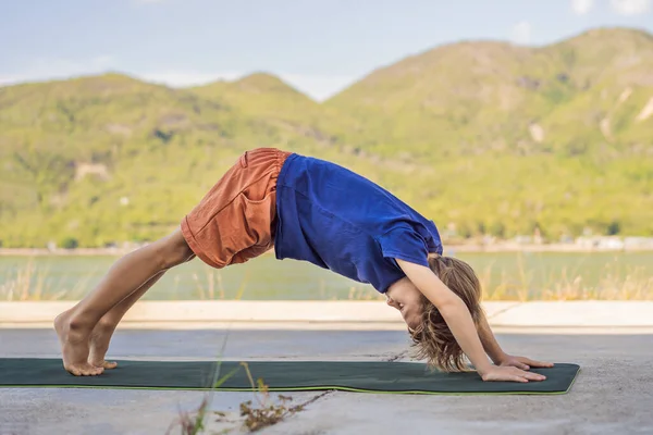 Junge macht Yoga auf einer Yogamatte vor dem Hintergrund der Berge — Stockfoto