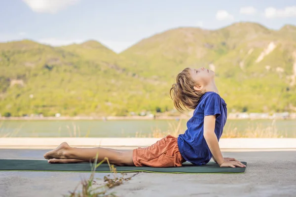 Junge macht Yoga auf einer Yogamatte vor dem Hintergrund der Berge — Stockfoto