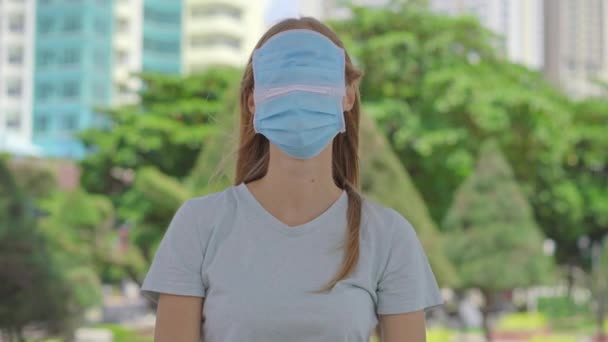 Eine junge Frau steht auf einer Straße. Sie trägt zu viele medizinische Gesichtsmasken. Sie versucht, sich vor dem Coronavirus zu schützen. Falsche Verwendung von Gesichtsmasken — Stockvideo