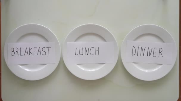 Жінка замінює написи сніданок, обід і вечерю на порожніх тарілках з написом пост. Інтервальна концепція голодування. Пропускати їжу — стокове відео