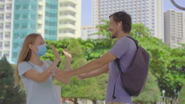 Een man zonder gezichtsmasker probeert een vrouw met een gezichtsmasker te omhelzen, maar ze laat hem dat niet doen omdat dat in strijd is met de sociale afstandelijke veiligheidsrichtlijnen. Sociaal afstandelijk concept. Covid-19 zelf — Stockvideo