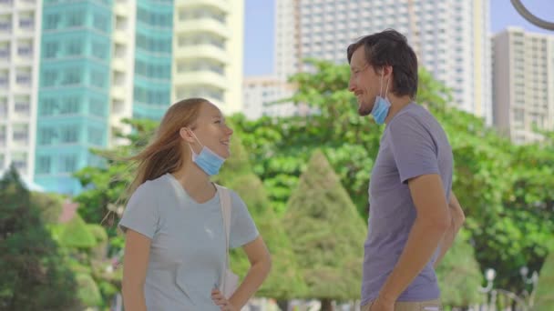 Dos jóvenes hombre y mujer se comunican usando máscaras médicas de la manera equivocada. Sus máscaras no cubren sus narices y bocas. Manera incorrecta de usar una máscara facial — Vídeo de stock