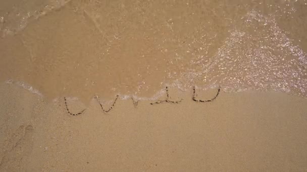 Slowmotion shot. A lettering COVID on the sand is being washed away by the sea. Concept of the end of the COVID pandemic — Stock Video