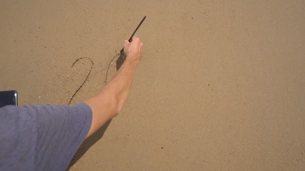 Lassított felvétel. Egy férfi 2021-et ír a homokra a parton, később az írást elmossa a tenger Az élet változásainak koncepciója. Az évek változása — Stock videók