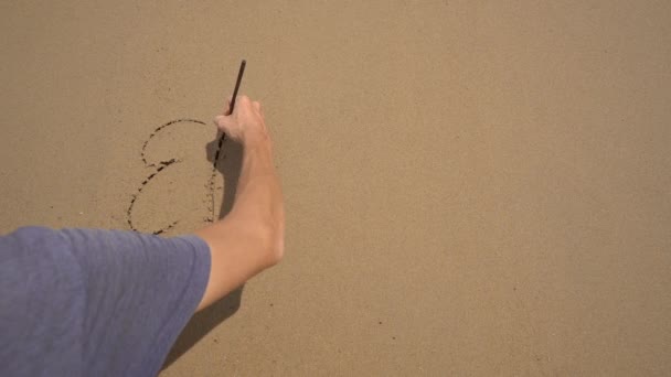 Επιβράδυνση. Ένας άνθρωπος γράφει γράμματα Σφάλμα στην άμμο σε μια παραλία — Αρχείο Βίντεο