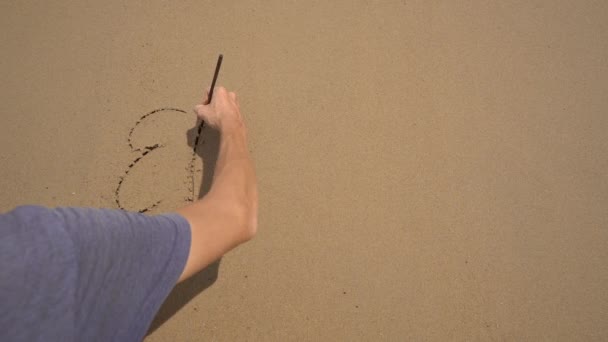 Disparo en cámara lenta. Un hombre escribe letras ERROR en la arena en una playa — Vídeo de stock