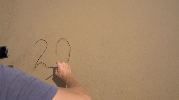 슬로우 모션 샷. 한 남자가 해변의 모래 위에서 2023 년에 글을 썼는데, 나중에 그 글은 삶의 변화에 대한 바다의 개념에 의해 씻어 지고 있다. 세월의 변화 — 비디오