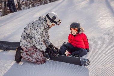 Babası oğluna snowboard öğretiyor. Kışın çocuklar için etkinlikler. Çocuklar kış sporu. Yaşam biçimi