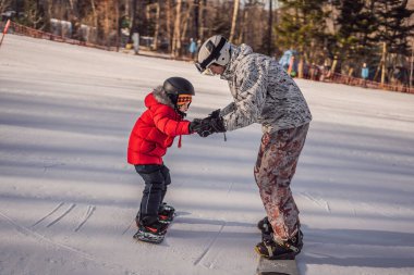 Babası oğluna snowboard öğretiyor. Kışın çocuklar için etkinlikler. Çocuklar kış sporu. Yaşam biçimi