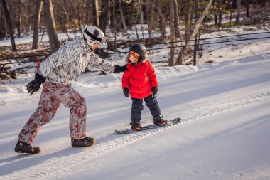 Babası oğluna snowboard öğretiyor. Kışın çocuklar için etkinlikler. Çocuklar kış sporu. Yaşam biçimi