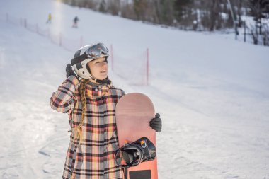 Güneşli bir kış gününde kayak merkezindeki kadın snowboardcu.