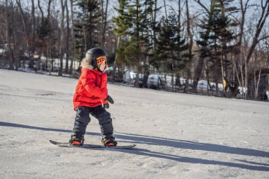 Küçük sevimli çocuk snowboard yapıyor. Kışın çocuklar için etkinlikler. Çocuklar kış sporu. Yaşam biçimi