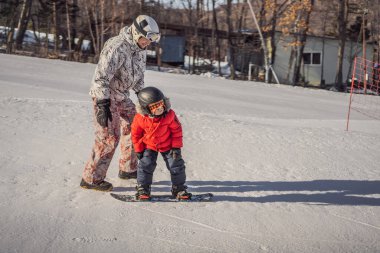 Babası oğluna snowboard öğretiyor. Kışın çocuklar için etkinlikler. Çocuklar kış sporu. Yaşam biçimi