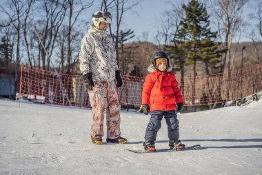 Babası oğluna snowboard öğretiyor. Kışın çocuklar için etkinlikler. Çocuklar kış sporu. Yaşam biçimi