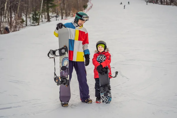 Instruktor snowboardu uczy chłopca jeździć na snowboardzie. Zajęcia dla dzieci w zimie. Zimowy sport dla dzieci. Styl życia — Zdjęcie stockowe