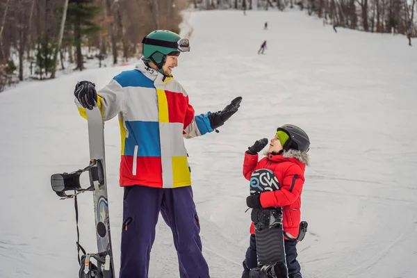 Instrutor de snowboard ensina um menino a snowboard. Atividades para crianças no inverno. Desporto de inverno das crianças. Estilo de vida — Fotografia de Stock