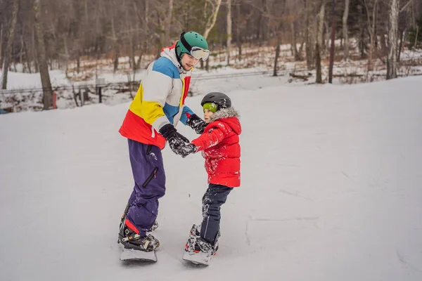 スノーボードインストラクターは少年にスノーボードを教える。冬の子供たちのための活動。子供冬のスポーツ。ライフスタイル — ストック写真