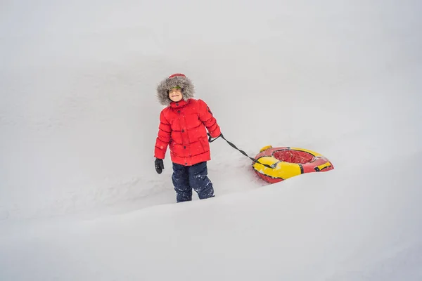 Dziecko bawiące się na snowtubie. Chłopak jedzie na rurze. Zimowa zabawa dla dzieci — Zdjęcie stockowe