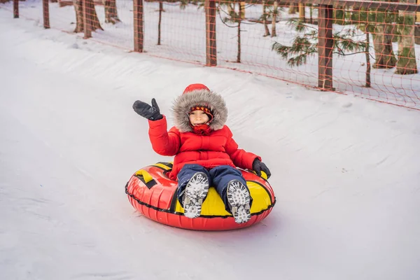 Niño divirtiéndose en tubo de nieve. El chico está montando un tubo. Diversión de invierno para niños — Foto de Stock