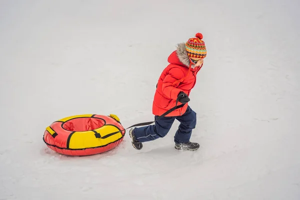 Das Kind hat Spaß auf der Schneekanone. Junge reitet auf einem Schlauch. Winterspaß für Kinder — Stockfoto