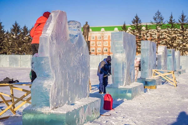 Rusko, Birabidzhan, 18. prosince 2019: Lidé prořezávají ledovou sochu motorovou pilou — Stock fotografie